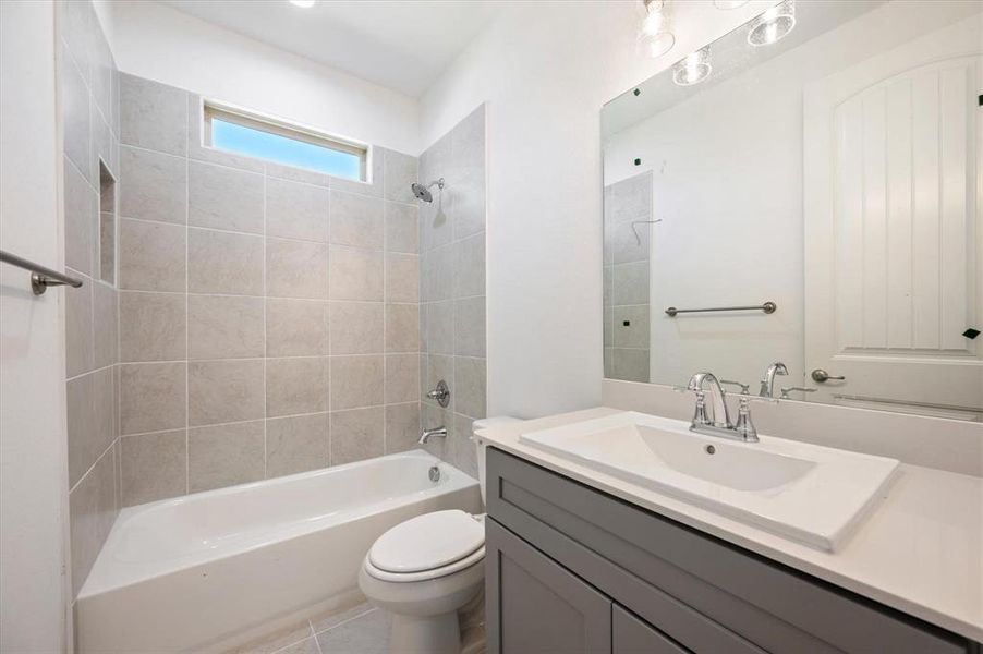 Full bathroom featuring toilet, tiled shower / bath combo, vanity, and tile patterned flooring