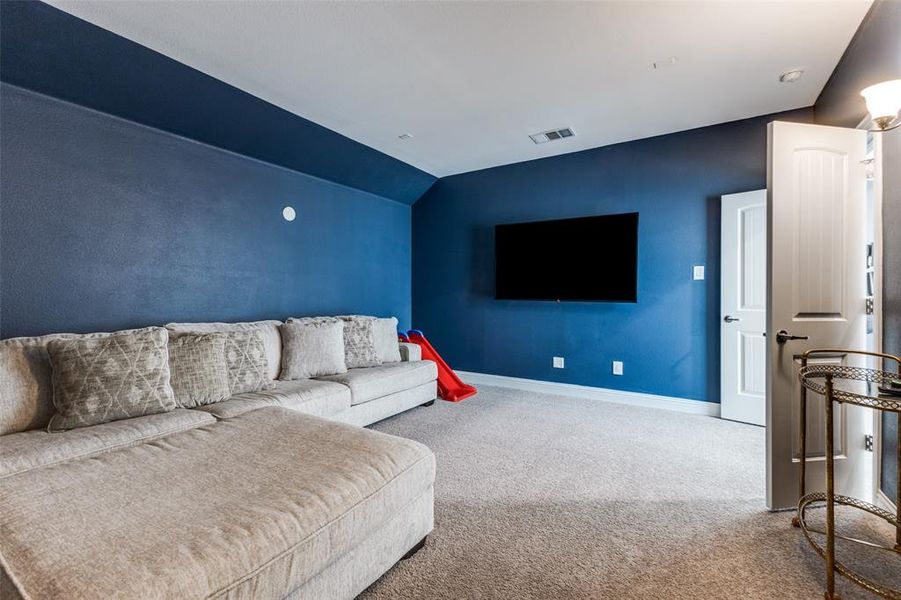 Media room featuring carpet flooring and vaulted ceiling