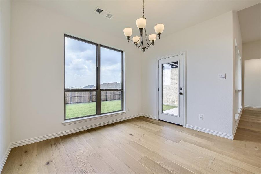 Empty room featuring a notable chandelier and light hardwood / wood-style flooring