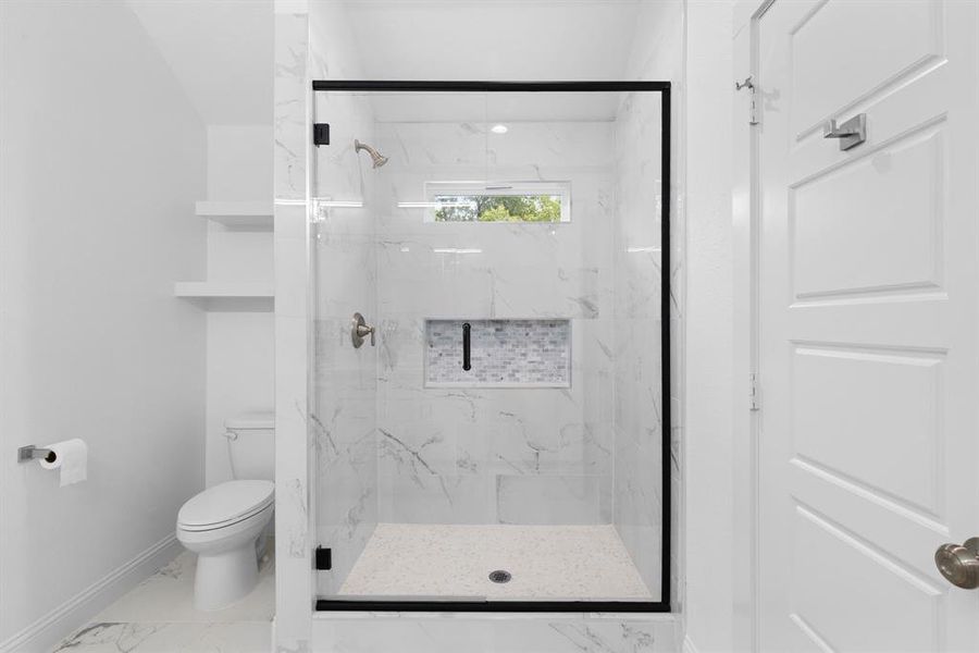 Bathroom featuring a shower with shower door and toilet