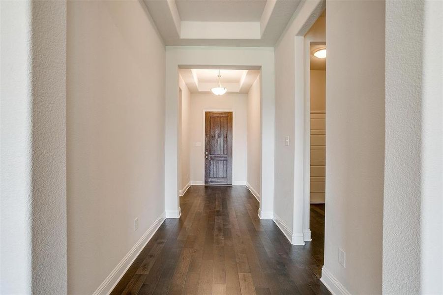 Corridor with a raised ceiling and dark hardwood / wood-style flooring