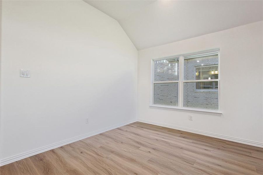 Spare room featuring light wood-type flooring and lofted ceiling