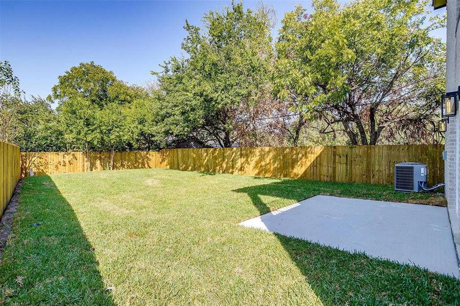 The private yard is surrounded by mature trees.