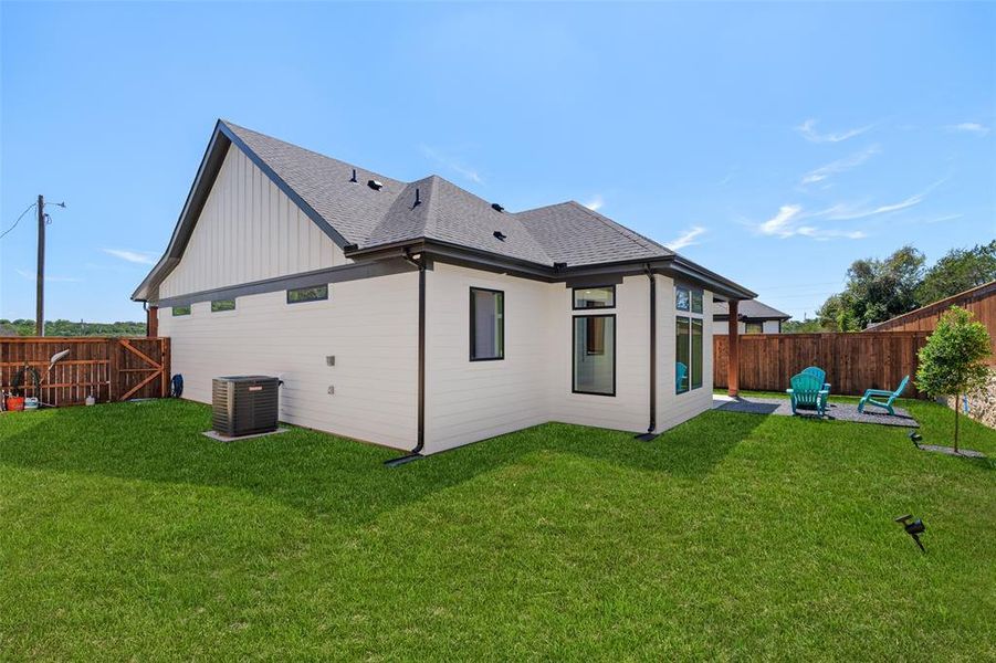 Rear view of property featuring cooling unit, a patio area, and a yard