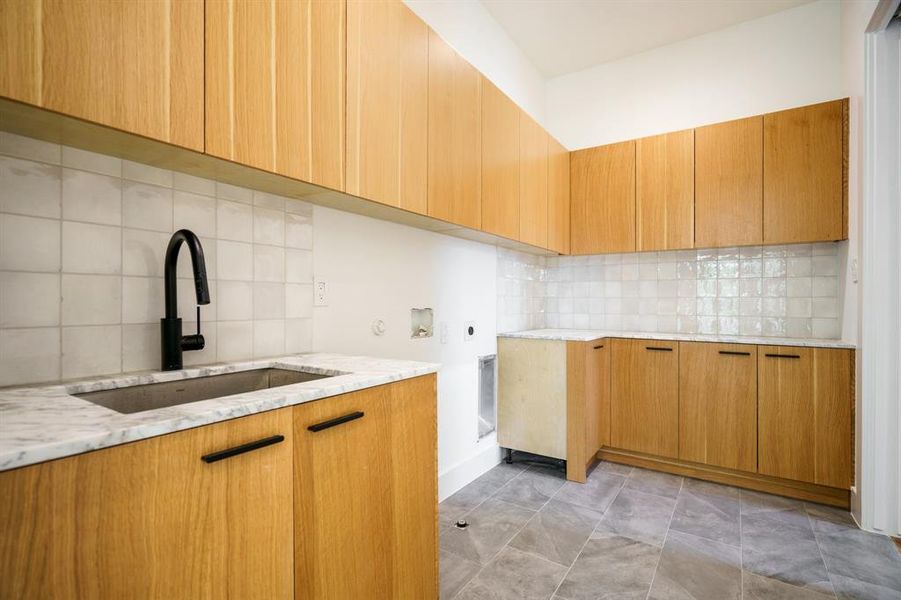 Kitchen featuring backsplash, sink, and light stone counters