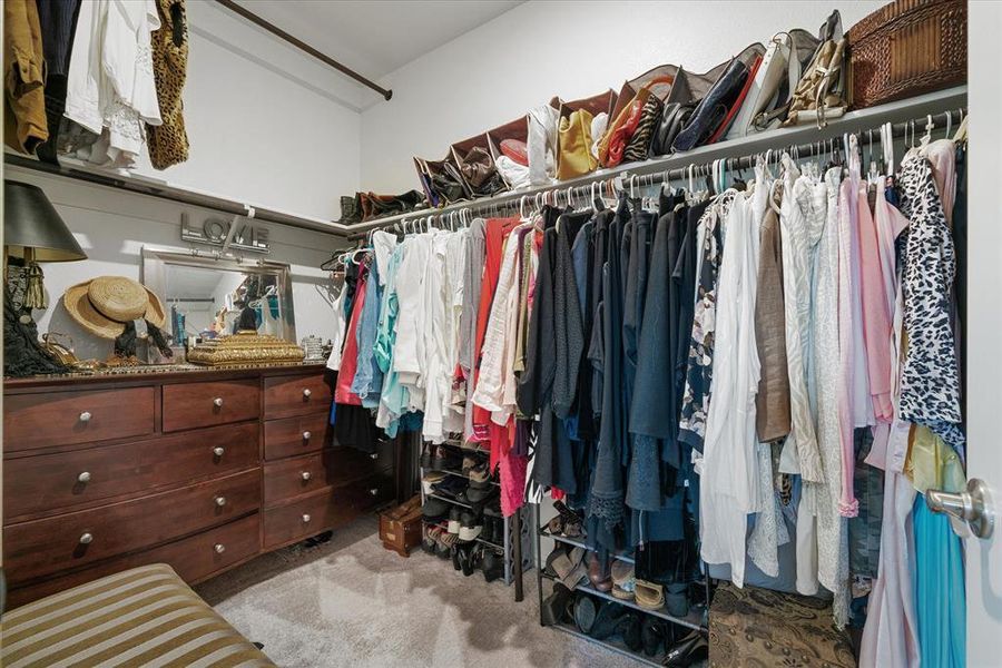 Spacious primary bedroom closet with light carpet.