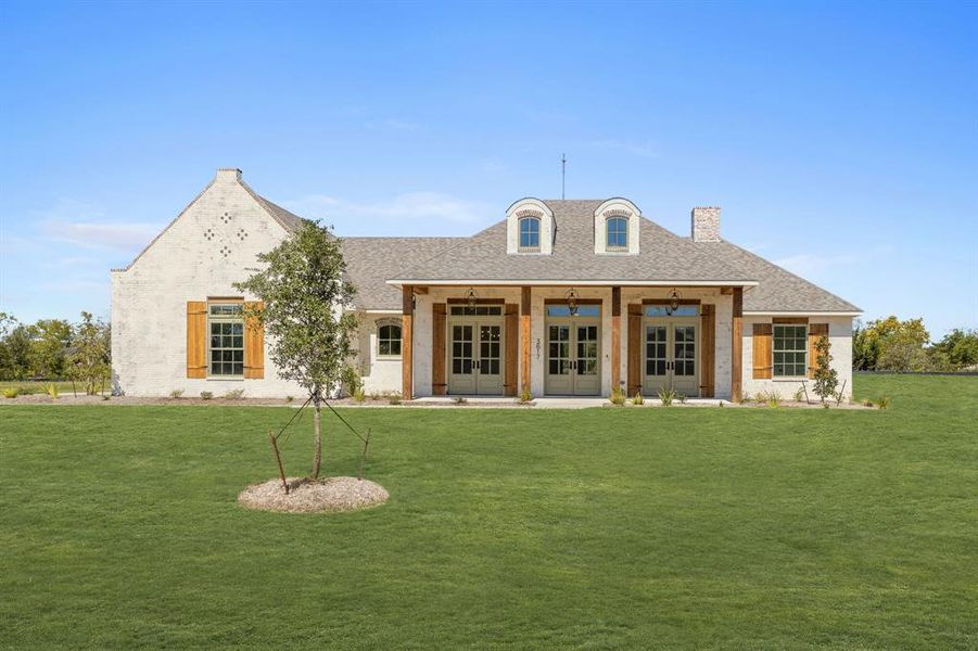 View of front of property with a front lawn, ceiling fan, and french doors