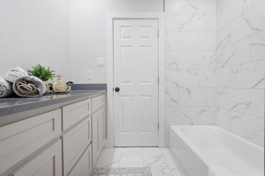 Bathroom featuring tiled shower / bath, vanity, and tile floors