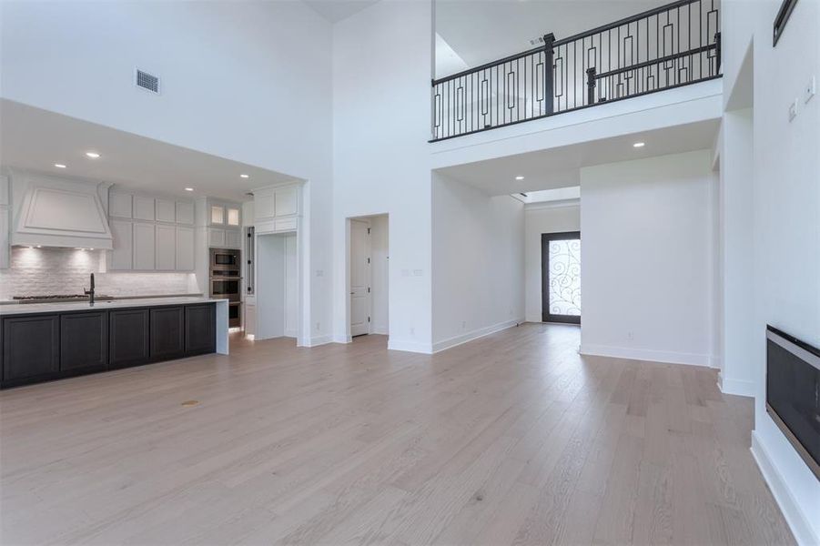 Unfurnished living room with a towering ceiling and light hardwood / wood-style floors