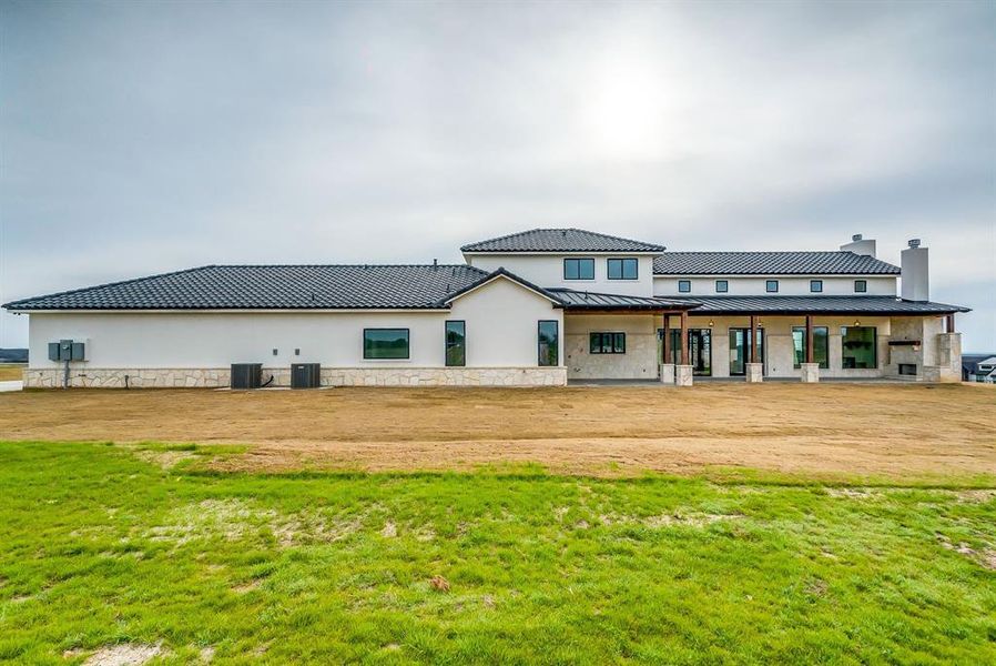 Back of property with central air condition unit and a lawn