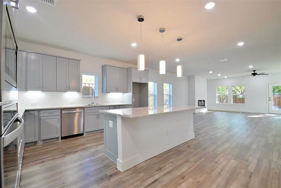 Kitchen featuring light hardwood / wood-style floors, a center island, stainless steel appliances, decorative light fixtures, and ceiling fan