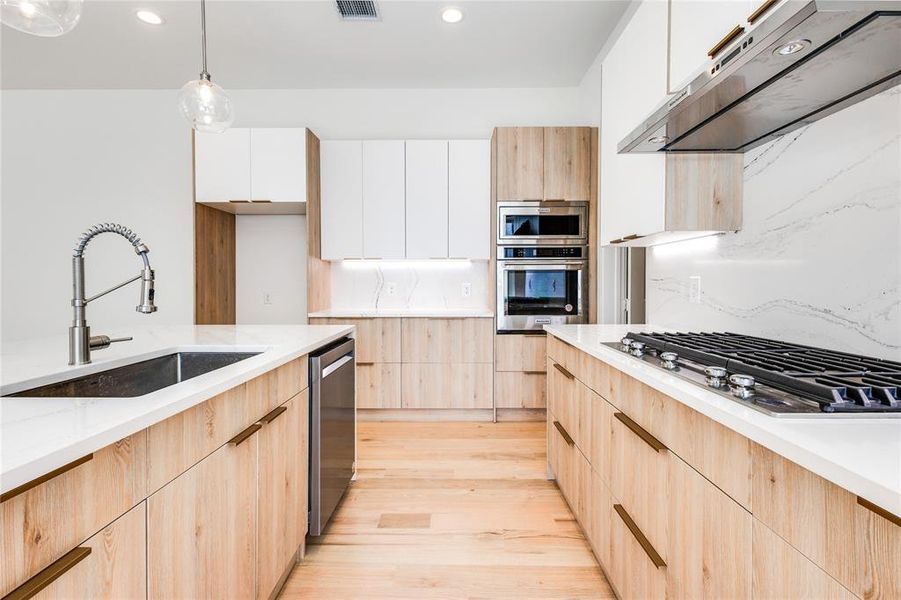 Kitchen featuring white cabinetry, stainless steel appliances, light hardwood / wood-style floors, light stone countertops, and extractor fan