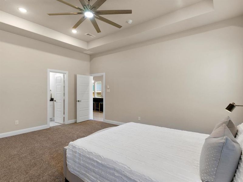 Bedroom featuring carpet floors, a tray ceiling, a towering ceiling, and ceiling fan