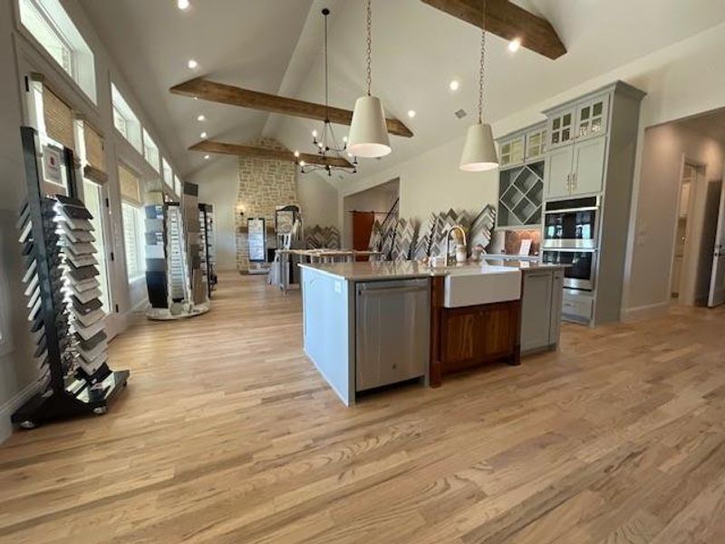 Kitchen featuring appliances with stainless steel finishes, sink, hanging light fixtures, high vaulted ceiling, and a center island with sink