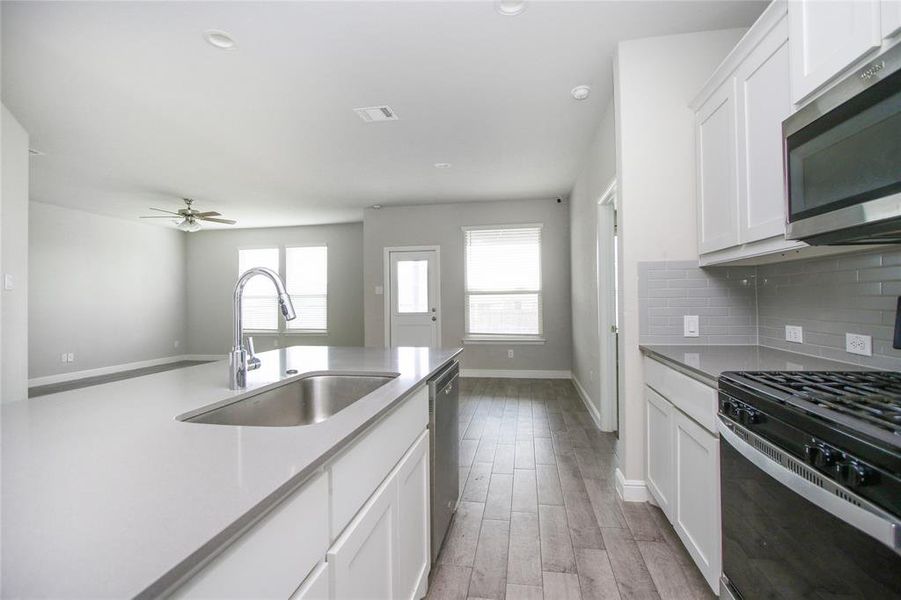 Kitchen featuring sink, backsplash, white cabinetry, appliances with stainless steel finishes