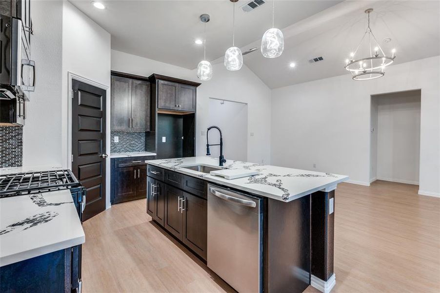 Kitchen featuring sink, appliances with stainless steel finishes, dark brown cabinets, and a kitchen island with sink