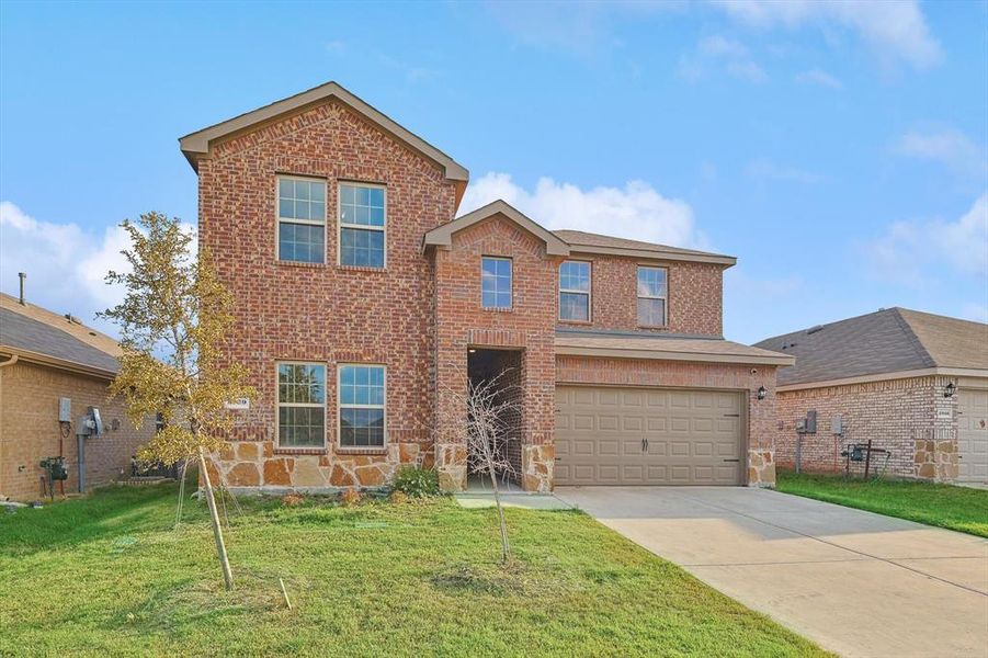 View of property featuring a garage and a front lawn