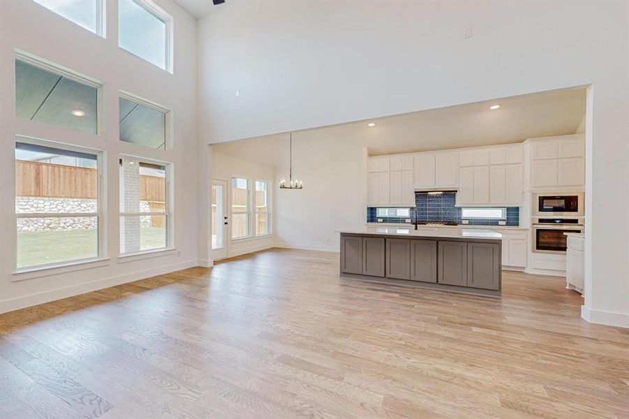 Kitchen featuring oven, decorative backsplash, light wood-type flooring, and a center island with sink