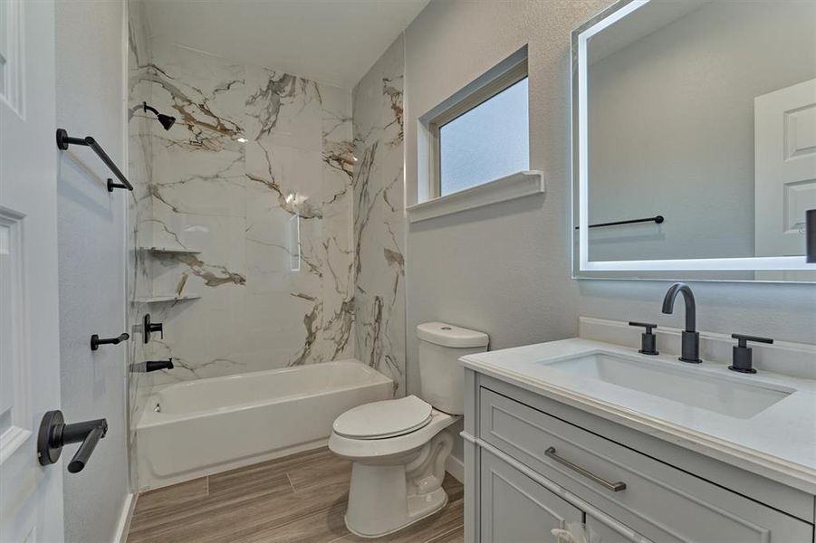 A full bath with coordinating wall tile, window for natural light and LED touch mirror with different light settings.