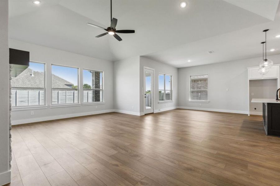 Unfurnished living room featuring sink, ceiling fan, vaulted ceiling, and wood-type flooring