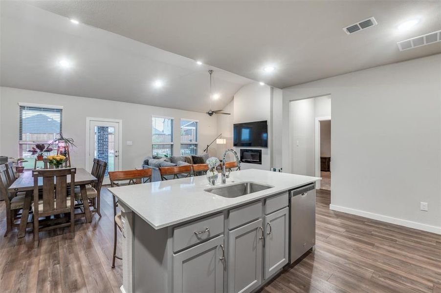 Kitchen featuring sink, dark hardwood / wood-style floors, dishwasher, and a kitchen island with sink