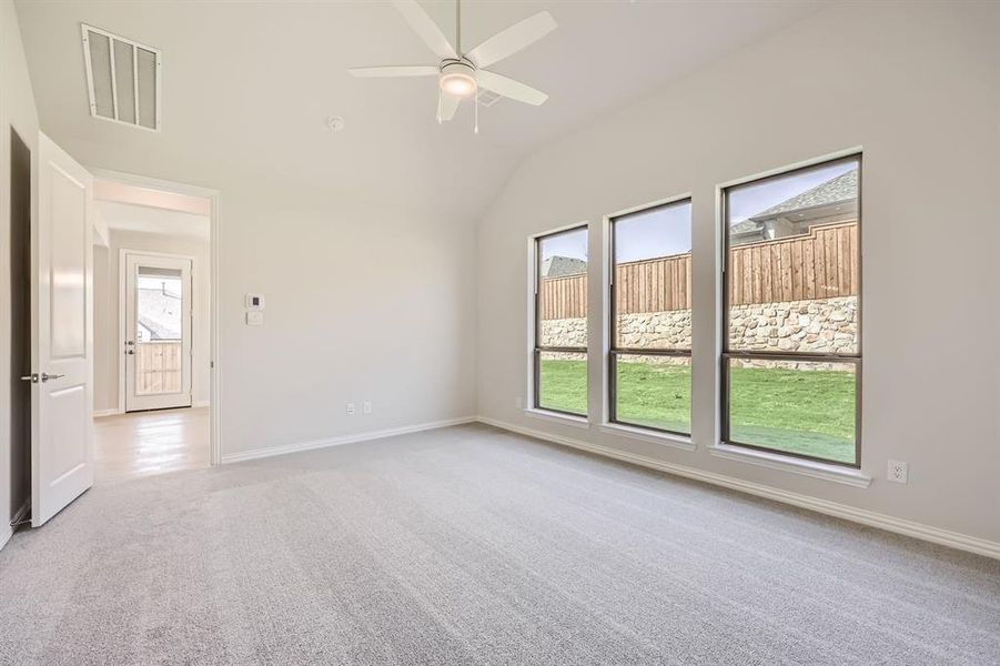 Spare room featuring light carpet, lofted ceiling, and ceiling fan