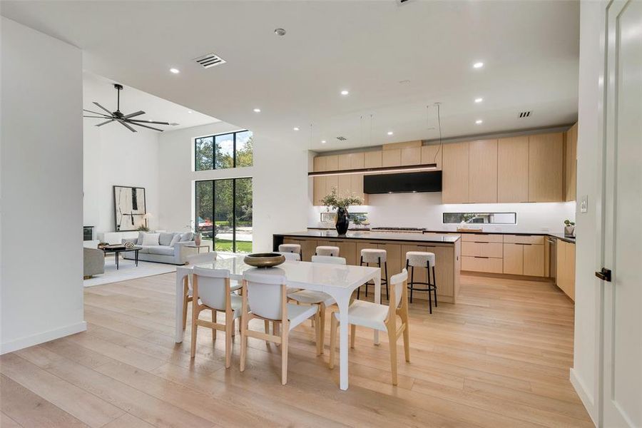 Dining area featuring light hardwood / wood-style flooring, a high ceiling, and ceiling fan