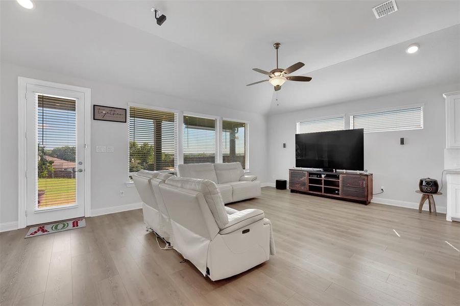 Living room with light wood-type flooring, vaulted ceiling, and ceiling fan