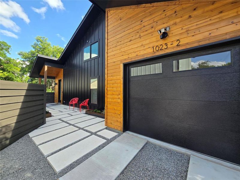 Custom large paver stone landscaping leading up to front door with metal planter boxes that provide just enough greenery. Drip irrigation in the planter boxes.