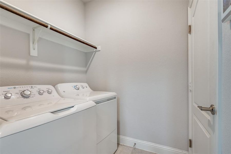 Laundry area featuring washing machine and dryer and light tile patterned floors