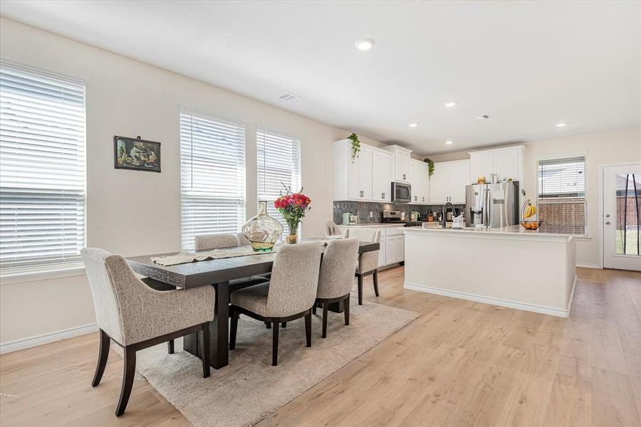 Dining area with light wood-type flooring and a healthy amount of sunlight