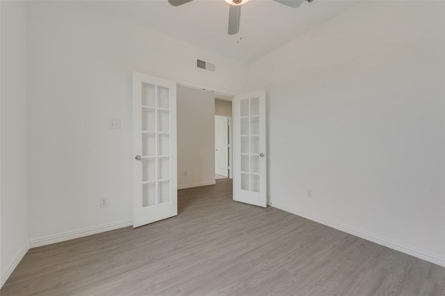 Empty room featuring ceiling fan, light hardwood / wood-style flooring, and french doors