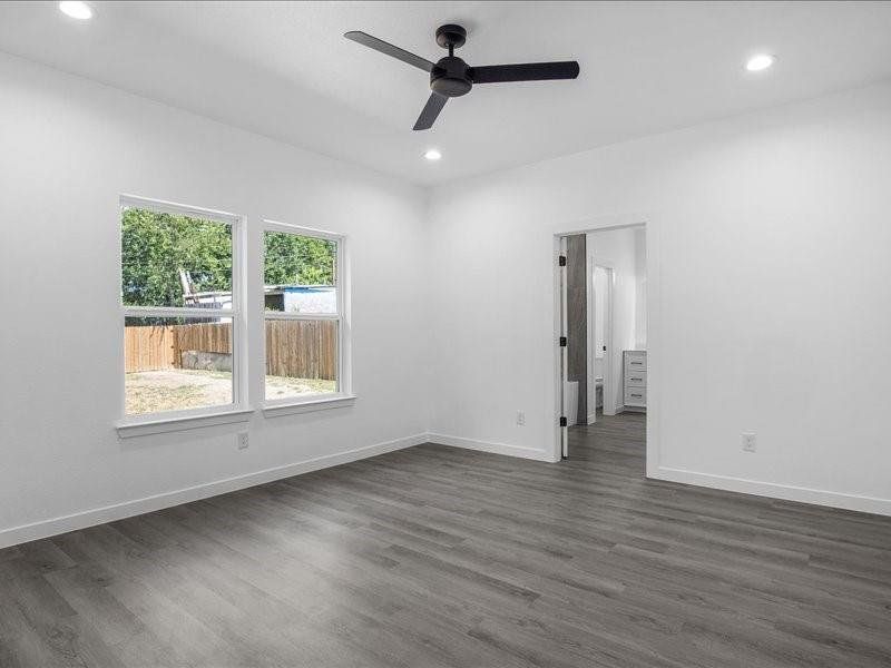 Empty room featuring dark hardwood / wood-style flooring and ceiling fan