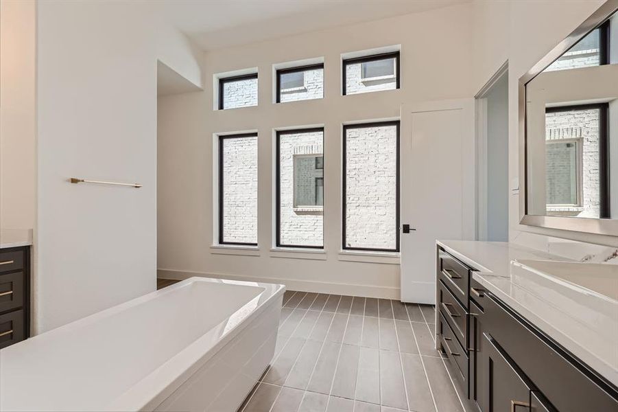 Bathroom featuring tile patterned flooring, vanity, and a relaxing tiled tub