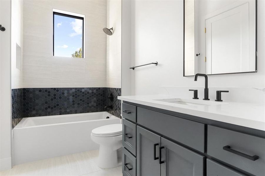 Bathroom with a tub to relax in, vanity, toilet, and tile patterned floors