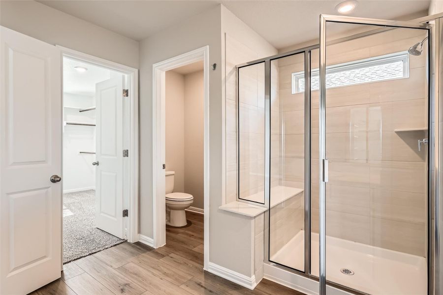 The spacious walk-in shower provides bench seating and comes wrapped in Avery White tile backsplash.