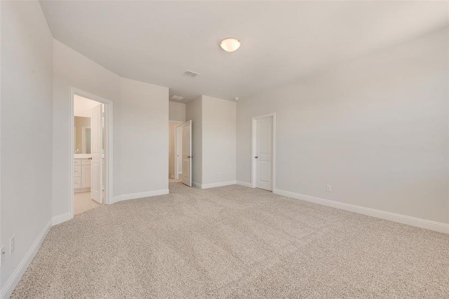 Unfurnished bedroom with connected bathroom and light colored carpet