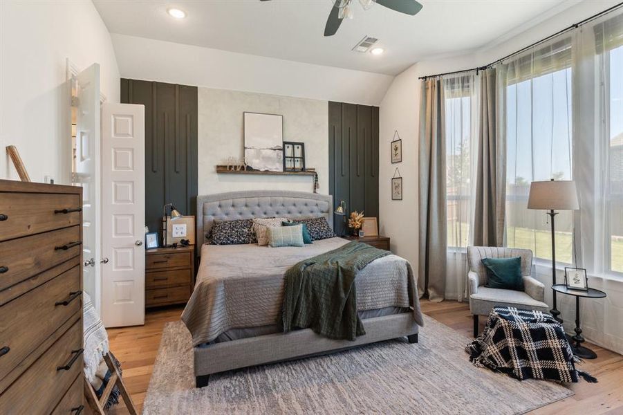 Bedroom with ceiling fan, light hardwood / wood-style floors, and vaulted ceiling