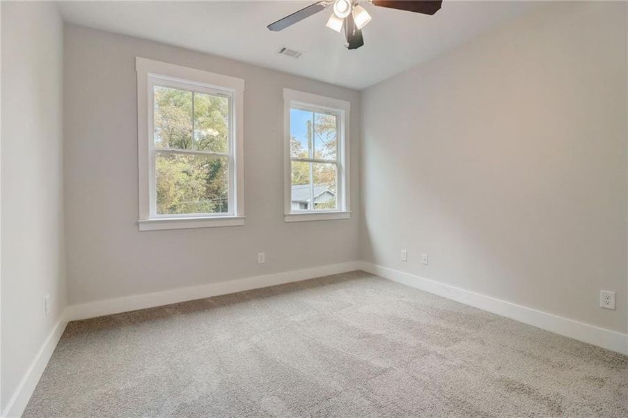 Carpeted spare room with ceiling fan and plenty of natural light