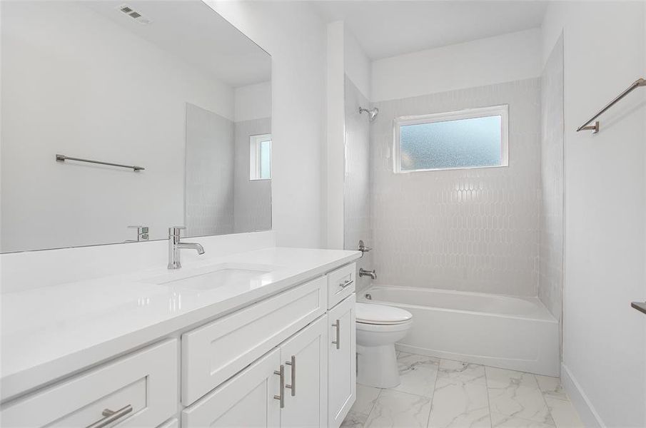 Full bathroom featuring tile patterned flooring, toilet, vanity, and tiled shower / bath