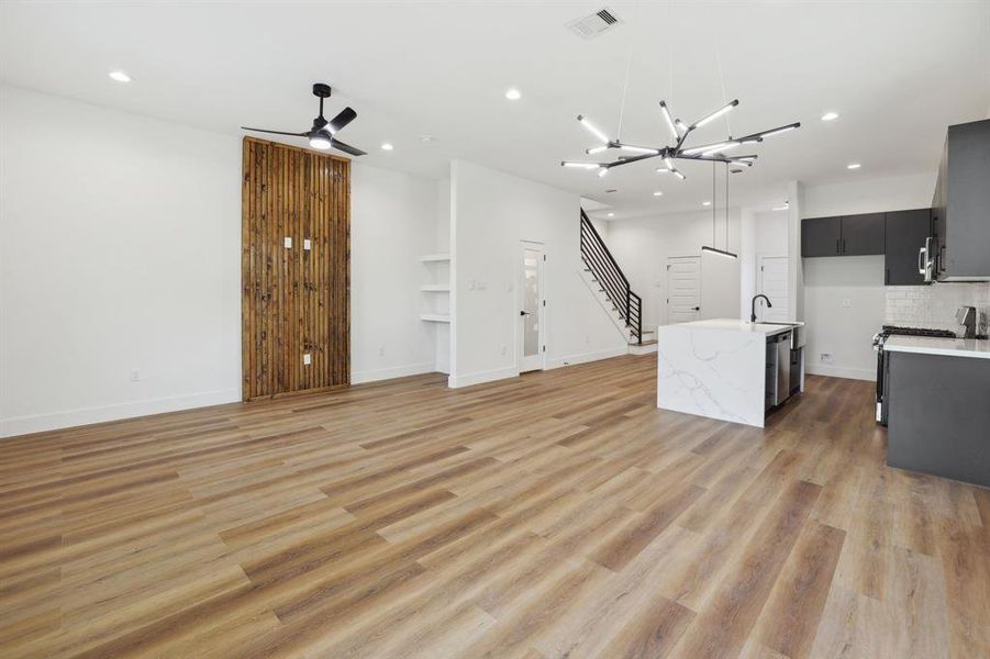 Living room with custom wall design, built in shelving/ desk nook, and designated dining area with overhead lighting.