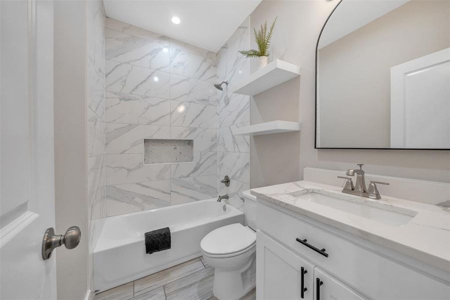 Full bathroom featuring tile patterned flooring, toilet, vanity, and tiled shower / bath