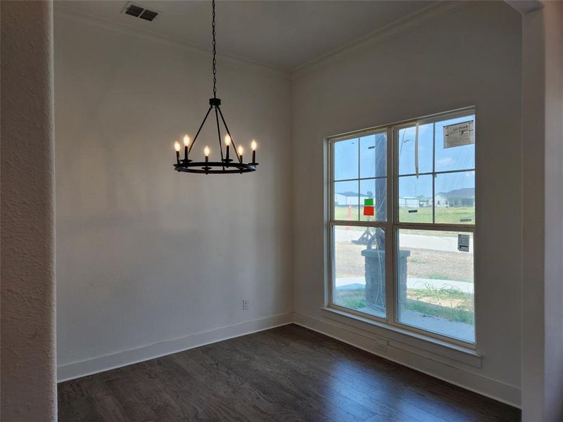 Unfurnished dining area with dark wood-type flooring, a chandelier, and crown molding