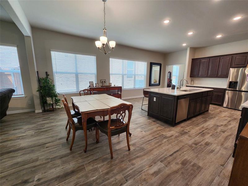 Kitchen with pendant lighting, an island with sink, sink, wood-type flooring, and stainless steel appliances