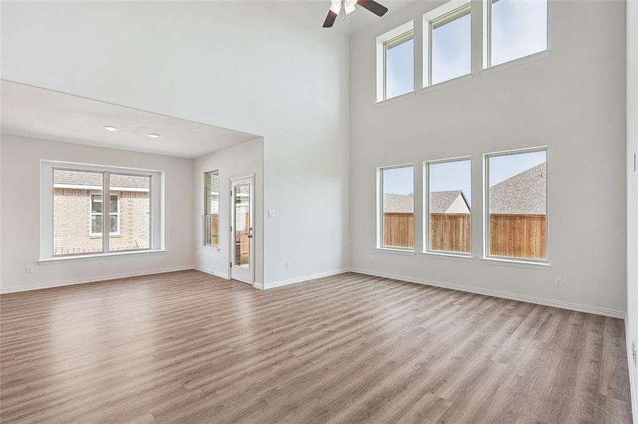 Unfurnished living room with ceiling fan, hardwood / wood-style floors, and a high ceiling