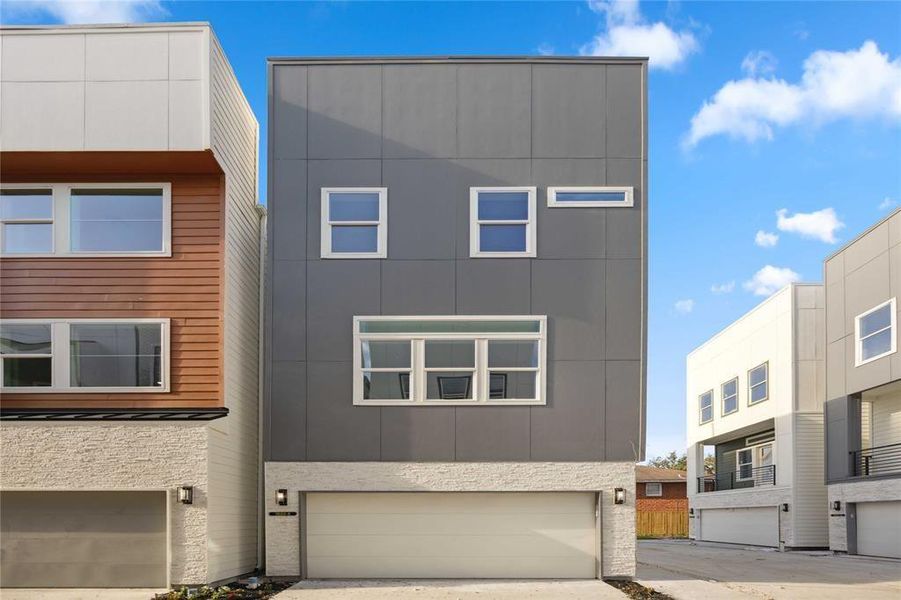 Modern brand new, three-story home with a sleek design, featuring large windows for ample natural light throughout, two-car garage, and neutral stone elevation.