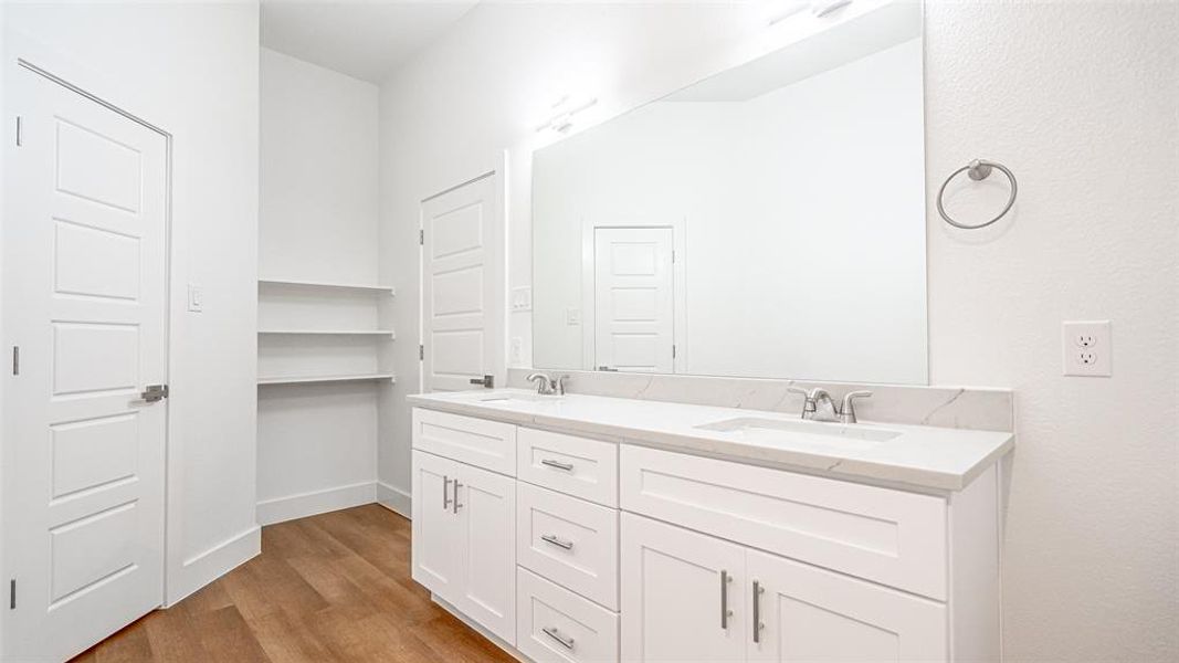 Primary Bathroom featuring wood-type flooring, dual sinks, and large vanity