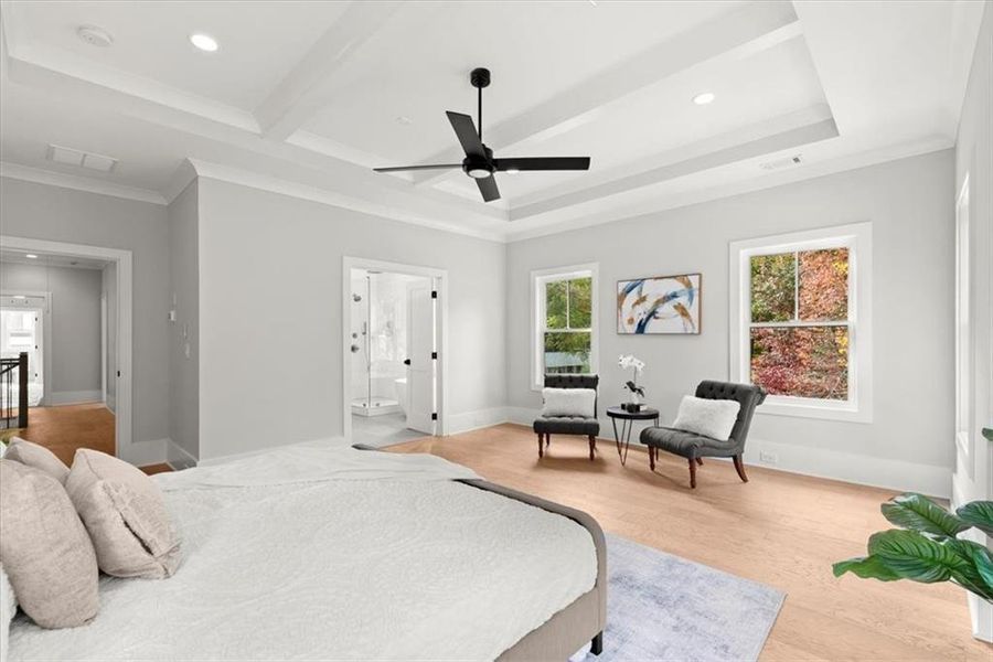 Bedroom with light hardwood / wood-style floors, a tray ceiling, ensuite bath, ornamental molding, and ceiling fan