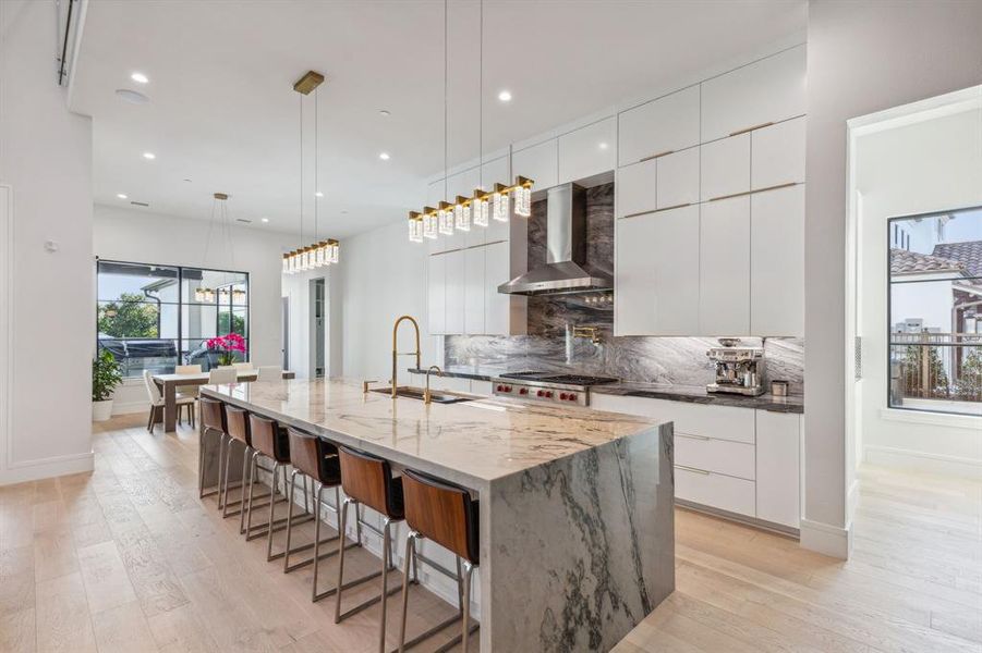 Kitchen with sink, decorative light fixtures, wall chimney exhaust hood, tasteful backsplash, and white cabinets