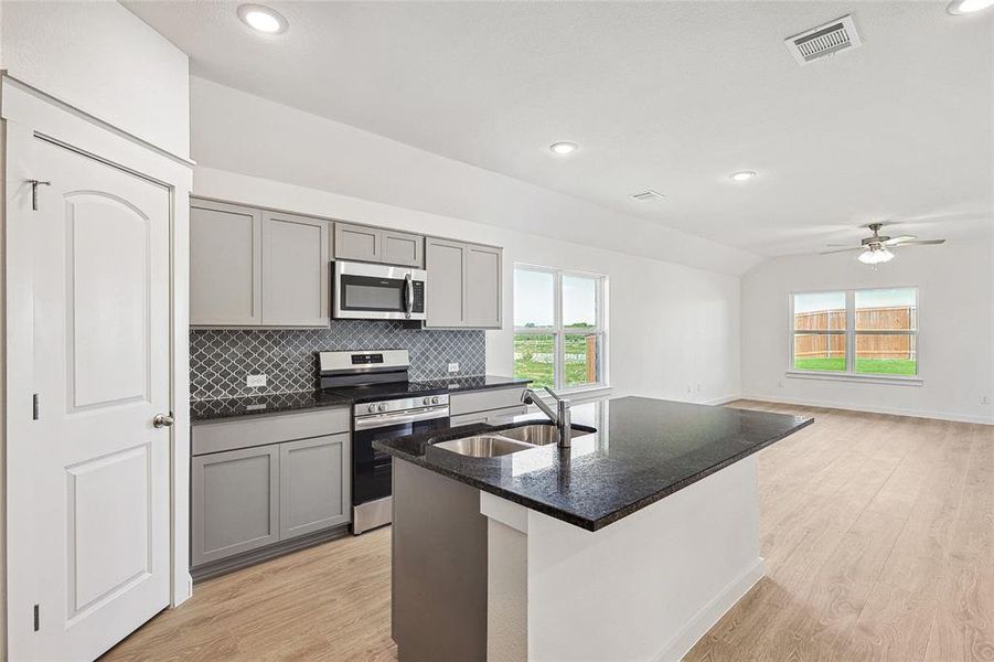 Kitchen with gray cabinetry, appliances with stainless steel finishes, sink, ceiling fan, and light wood-type flooring